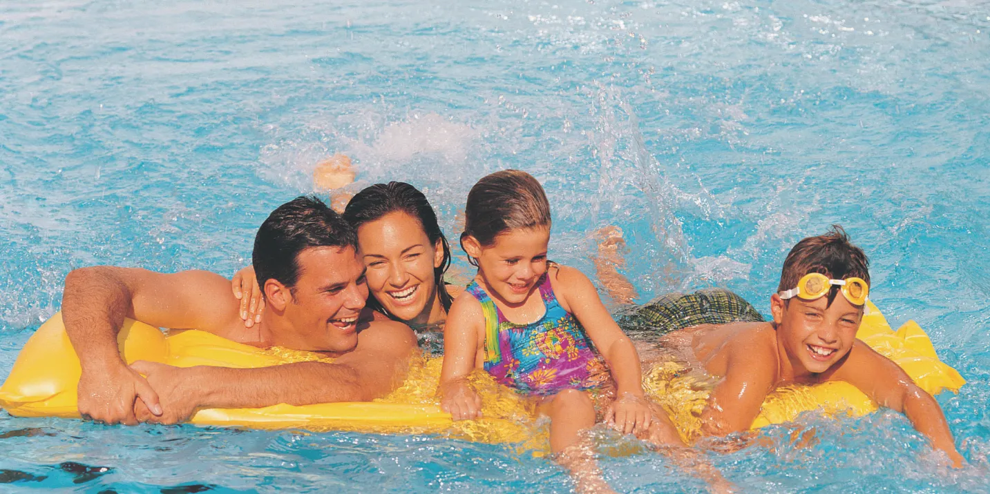 Foto familiar sonriendo disfrutando de la piscina